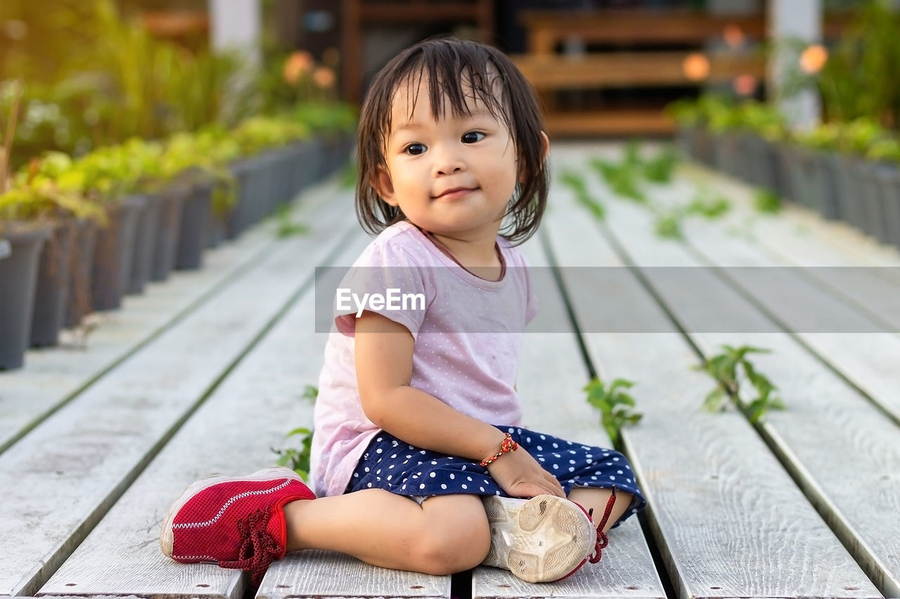 Baby girl sitting on footpath