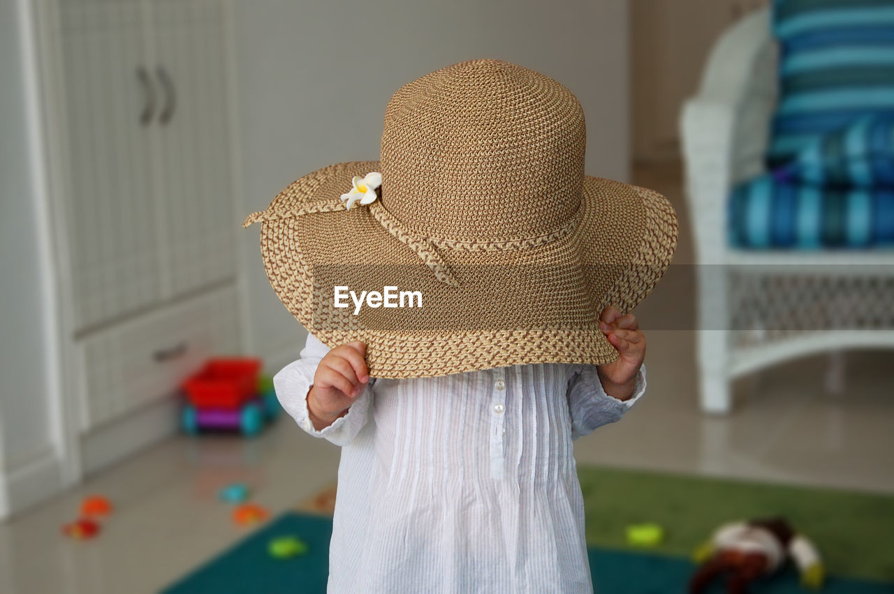Baby girl playing peek a boo with sun hat