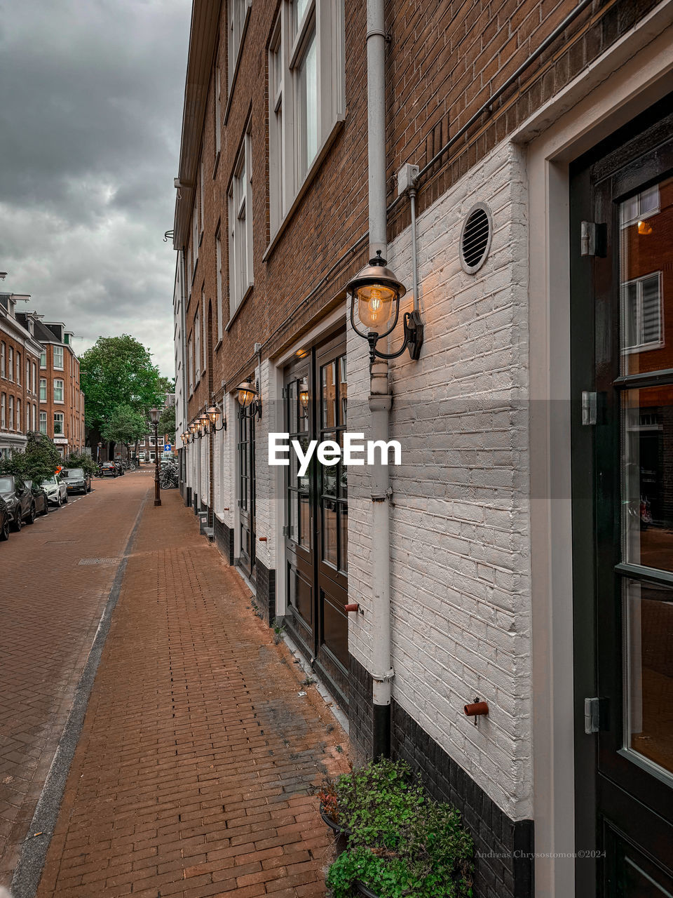 architecture, building exterior, road, built structure, street, city, neighbourhood, town, urban area, alley, building, residential area, residential district, lane, cloud, house, footpath, infrastructure, no people, sky, nature, city street, wall, outdoors, street light, the way forward, facade, day, transportation, travel destinations, cobblestone, window, diminishing perspective, sidewalk, walkway, downtown, plant, city life, road surface