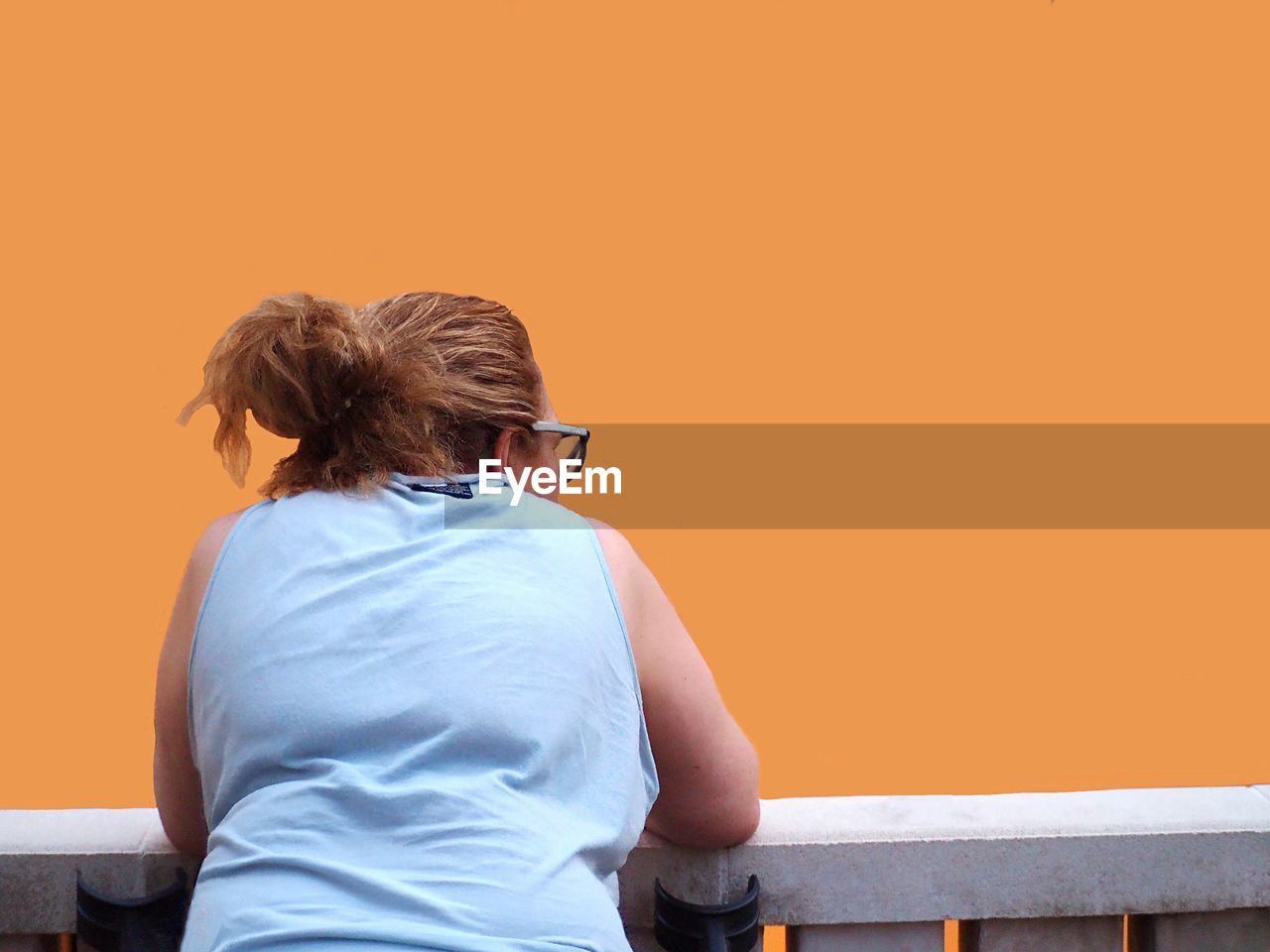 Rear view of woman standing against orange wall