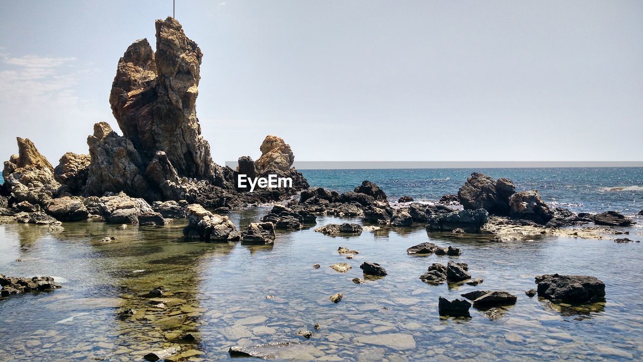 Rocks on sea shore against sky