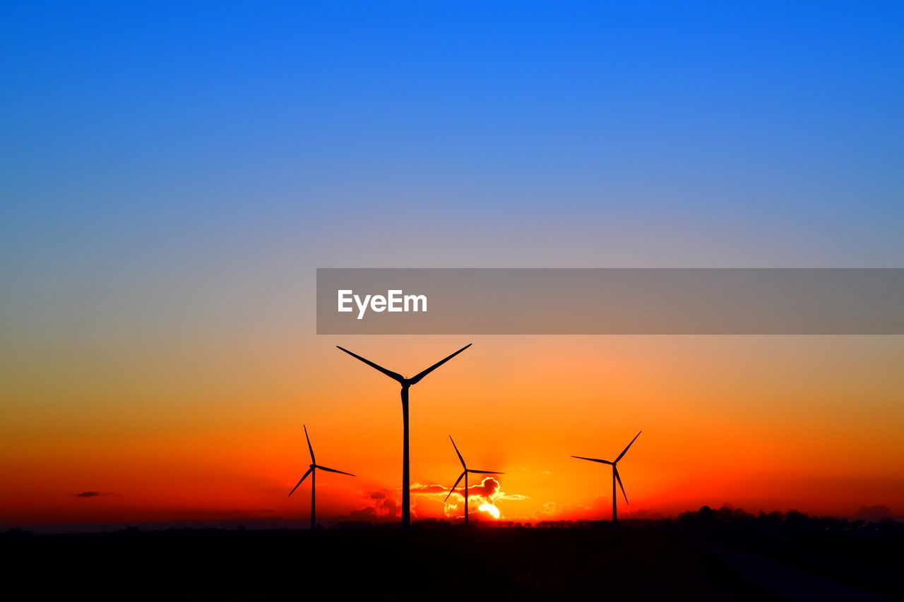 SILHOUETTE WIND TURBINES ON LAND DURING SUNSET