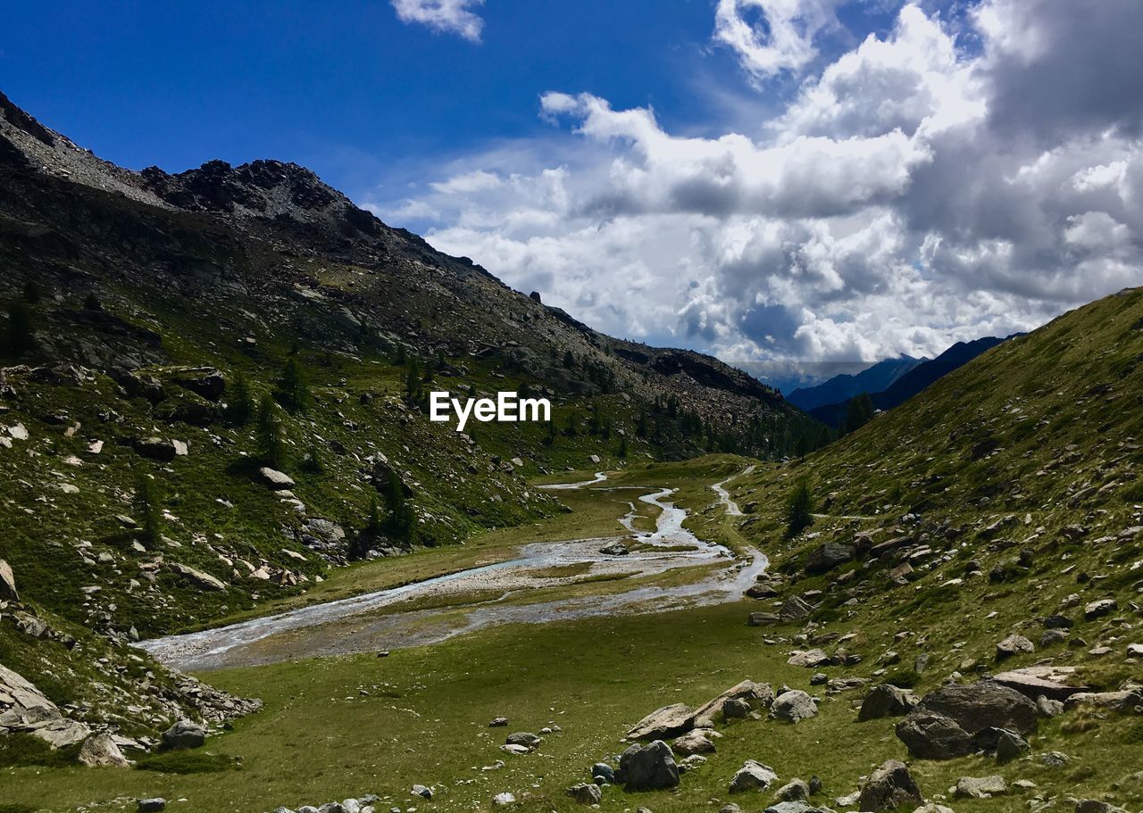 Scenic view of stream amidst mountains against sky