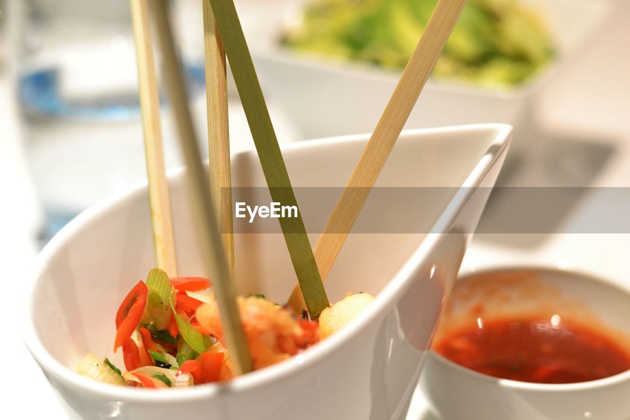 Close-up of food served in bowl with chopsticks