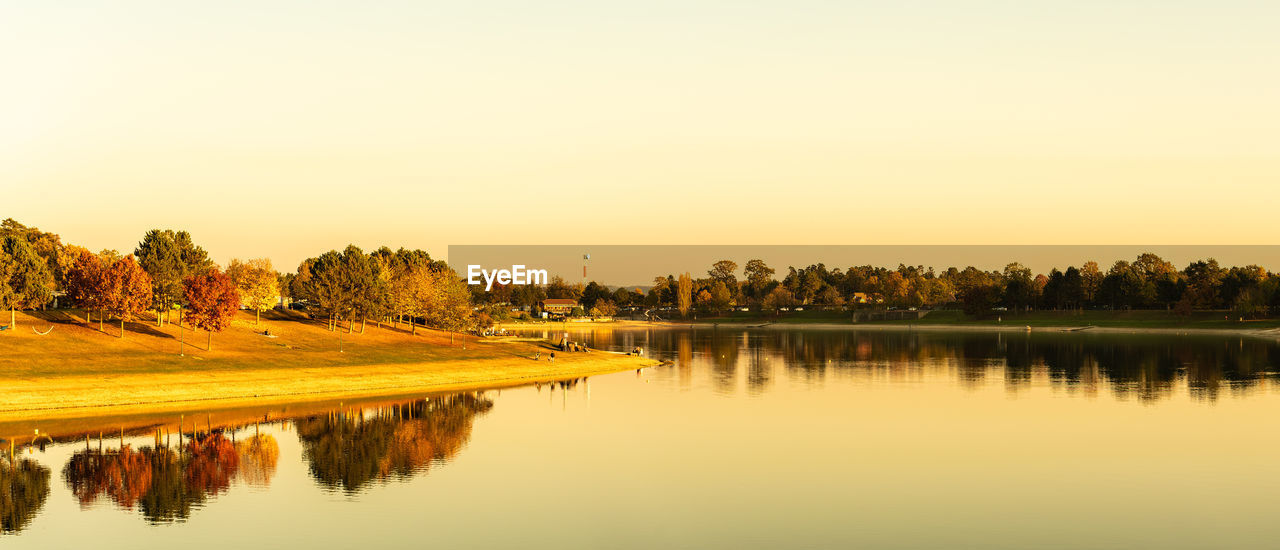 SCENIC VIEW OF LAKE AGAINST CLEAR SKY AT SUNSET