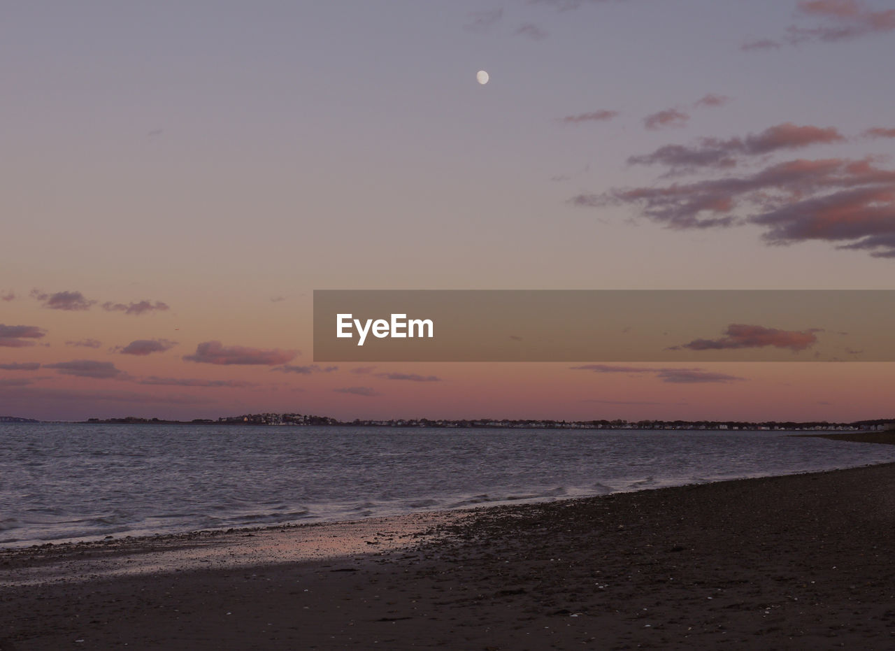 SCENIC VIEW OF BEACH AGAINST SKY AT SUNSET