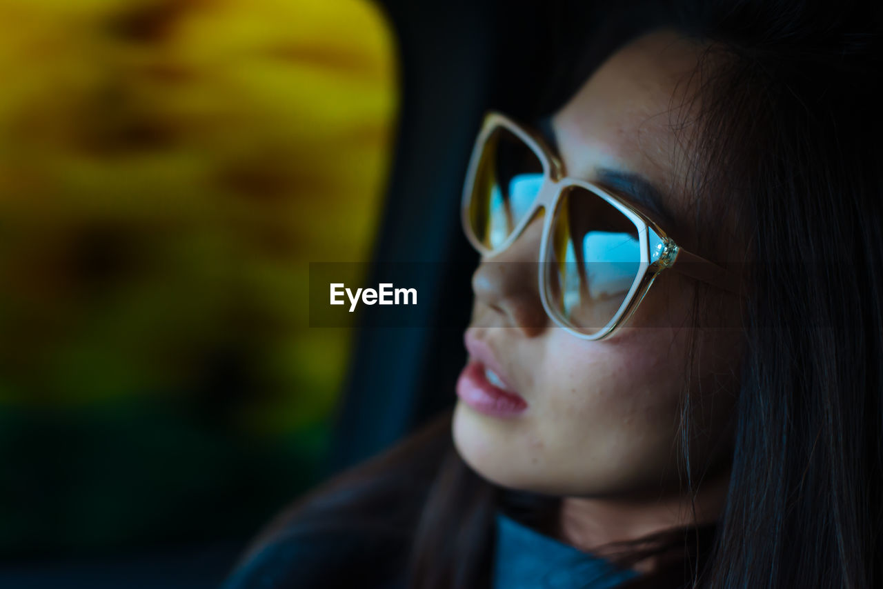 Close-up of young woman wearing sunglasses sitting in car
