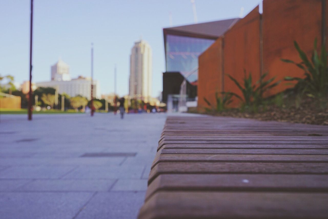 SURFACE LEVEL OF EMPTY ROAD WITH BUILDINGS AGAINST CLEAR SKY