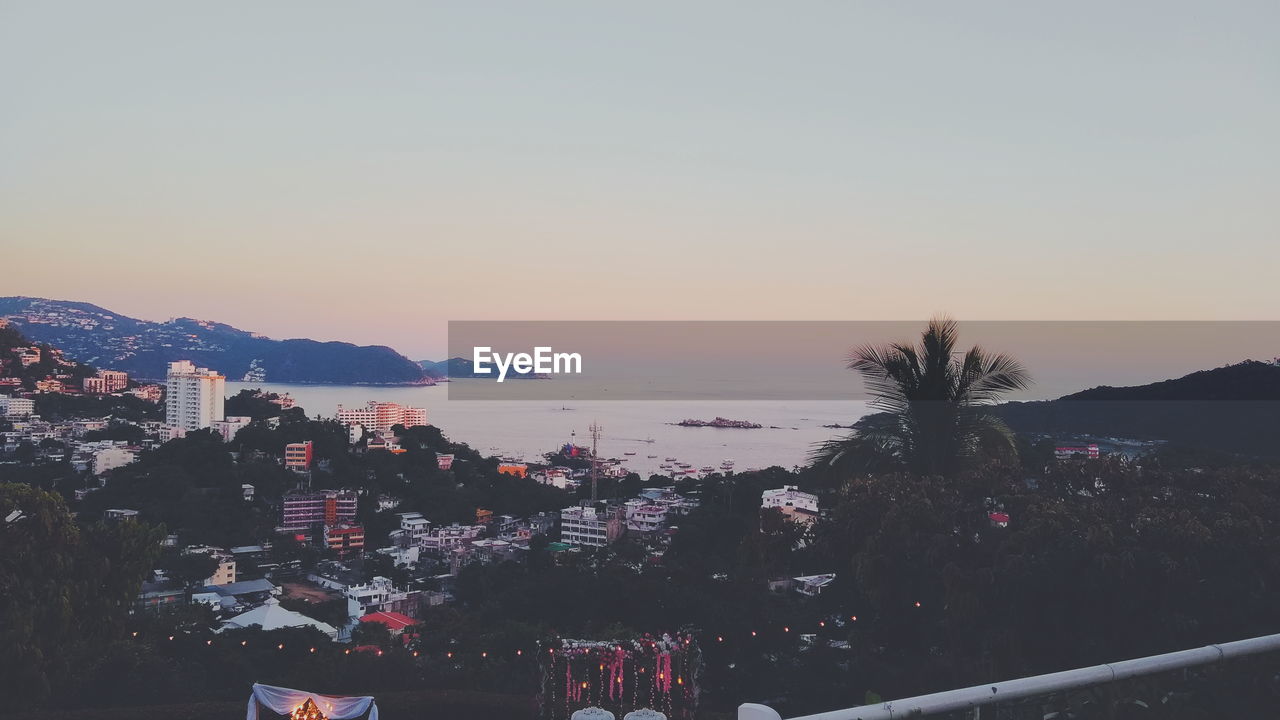 Scenic view of sea and buildings against sky during sunset