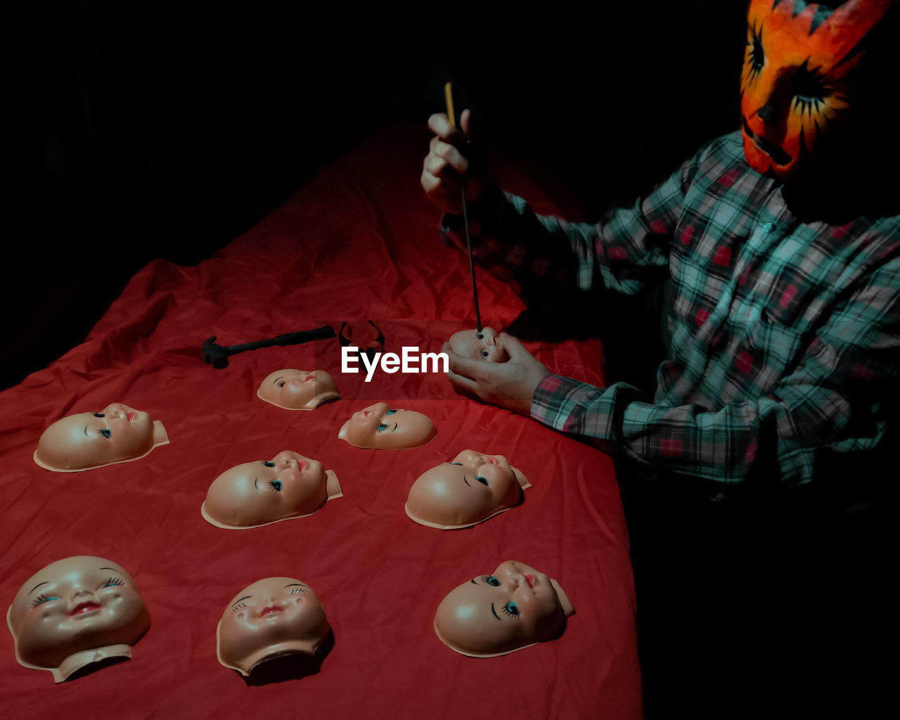Man wearing mask making toys on red tablecloth