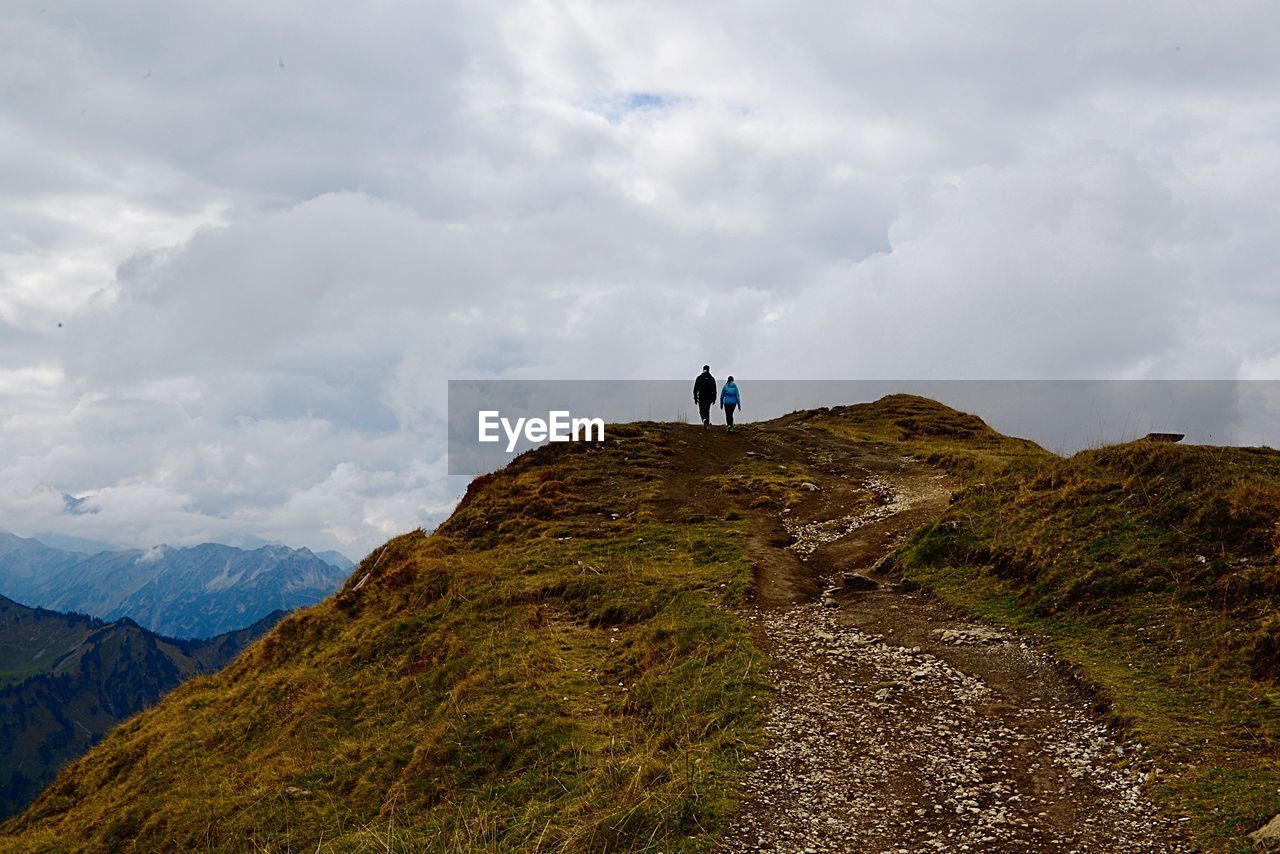 Rear view of hikers walking on mountain against sky