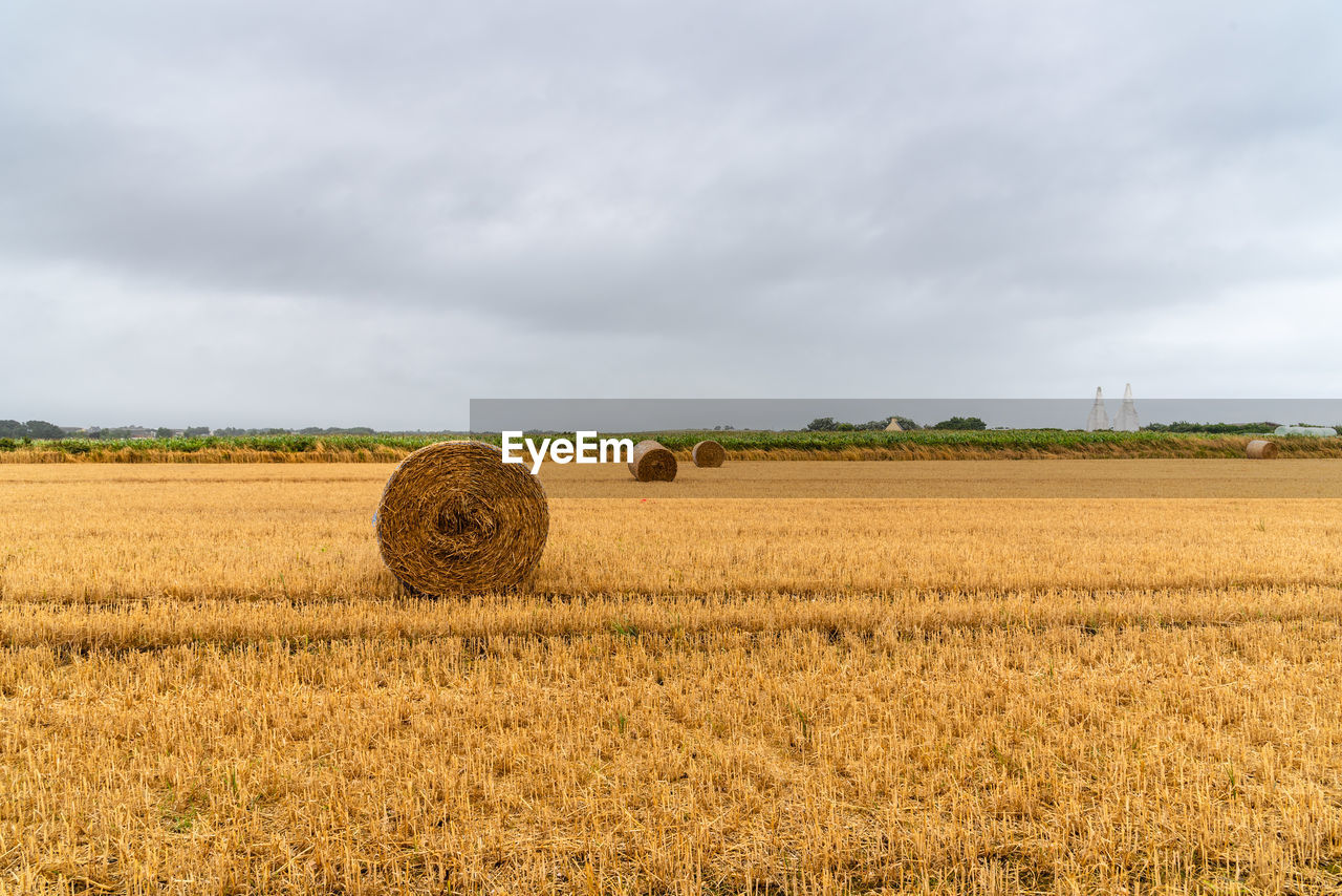 Hay bales on field against sky