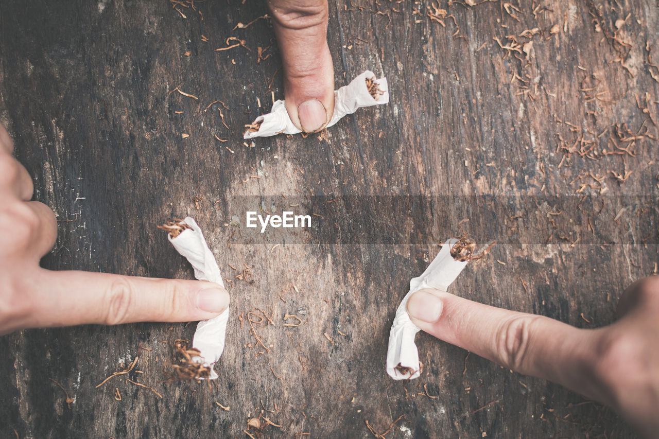 Cropped image of fingers crushing cigarettes