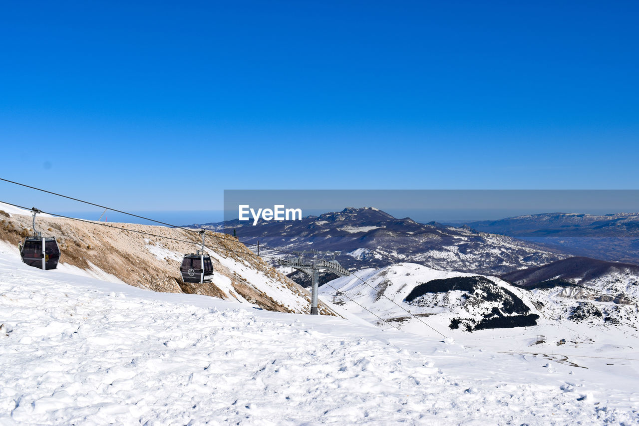 Scenic view of snowcapped mountains against clear blue sky