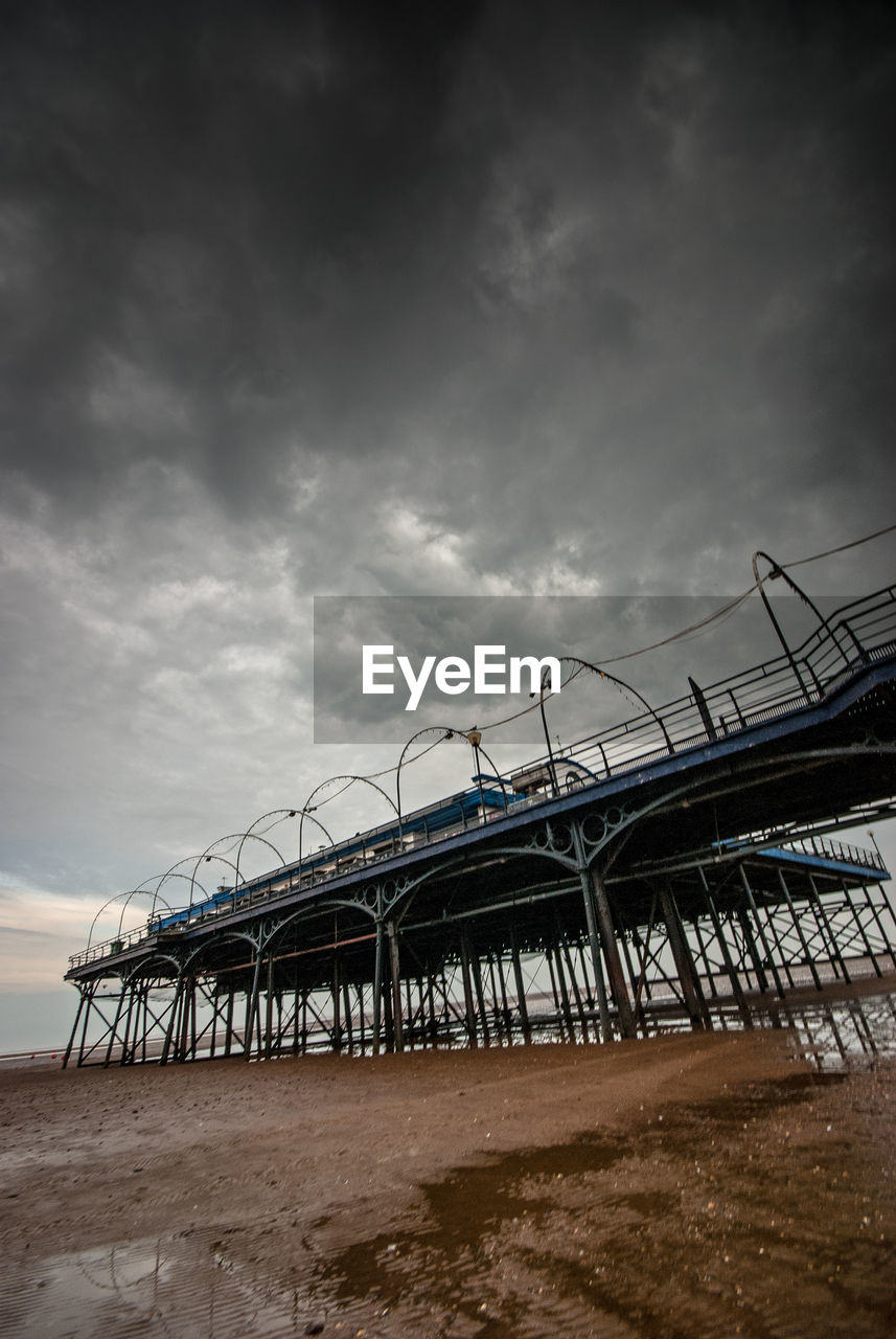 Low angle view of structure on beach against cloudy sky