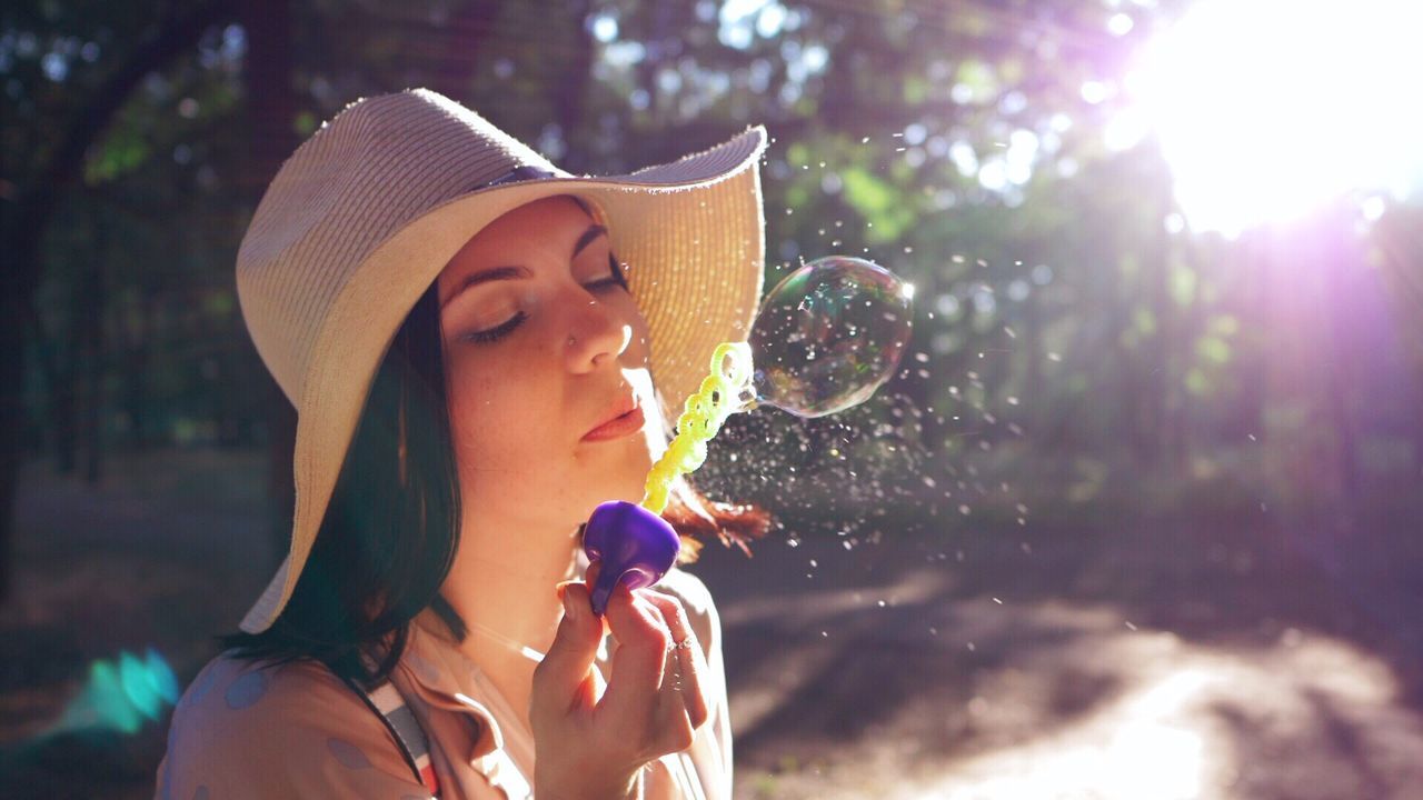 Close-up of young woman with bubbles in mid-air