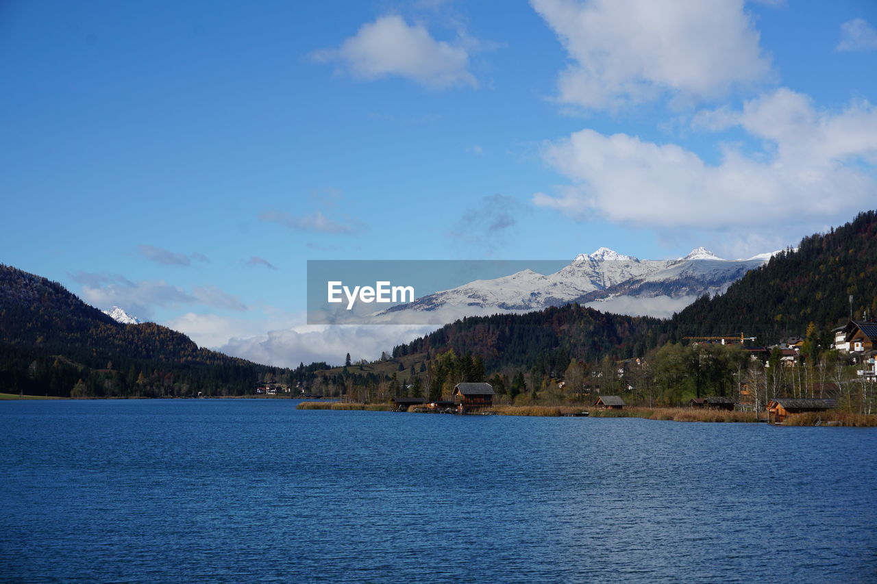scenic view of sea by snowcapped mountains against sky