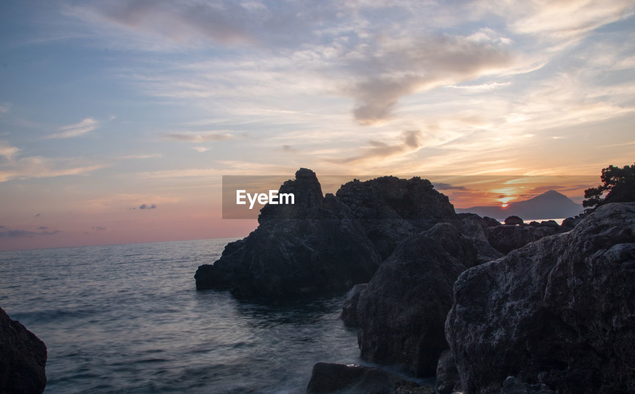 ROCKS ON SEA AGAINST SKY AT SUNSET