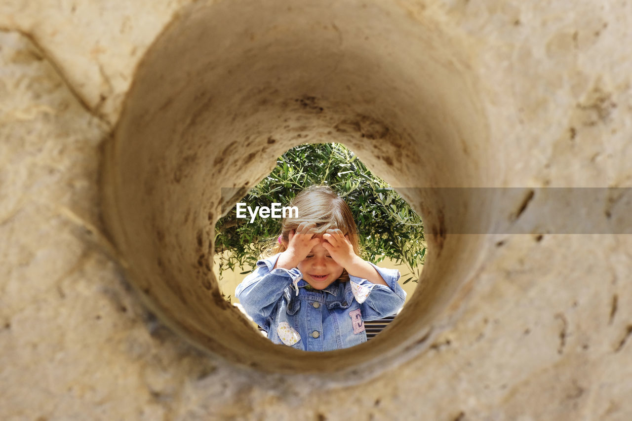 Girl with hand in hair seen through hole