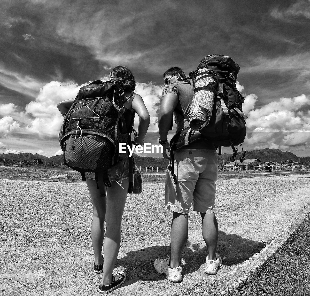 Rear view of friends walking on road against sky