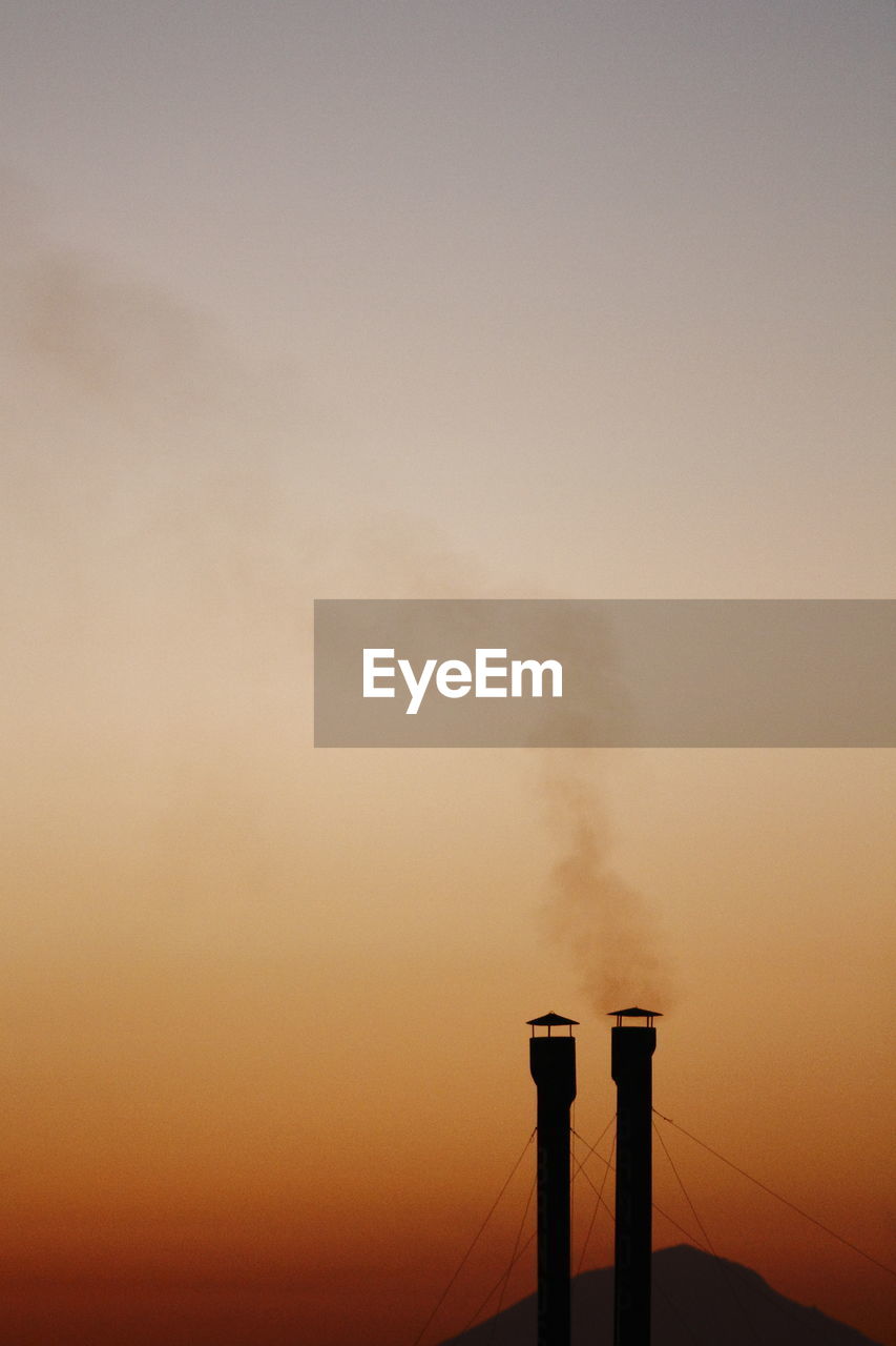 Smoke emitting from chimney against sky at sunset