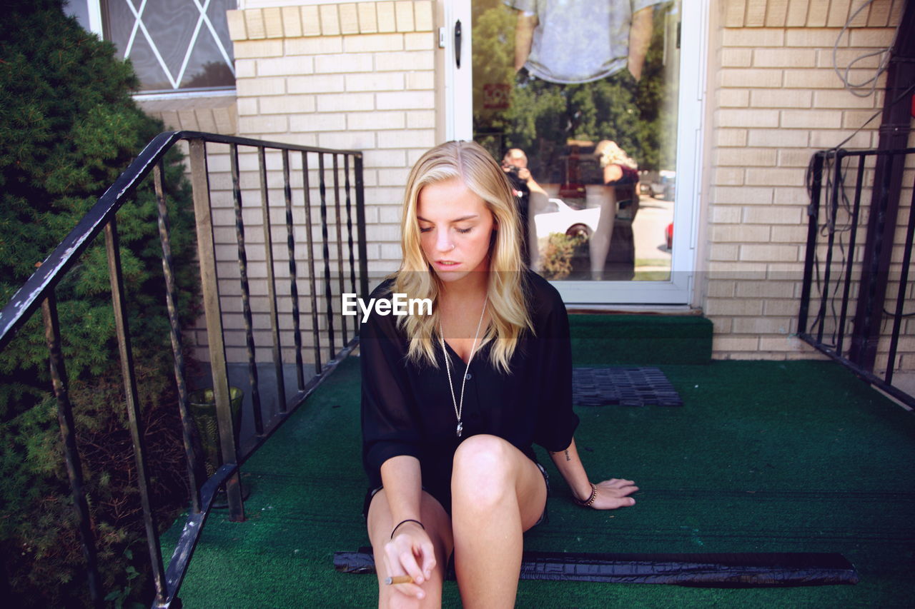 Young woman smoking while sitting on stairway