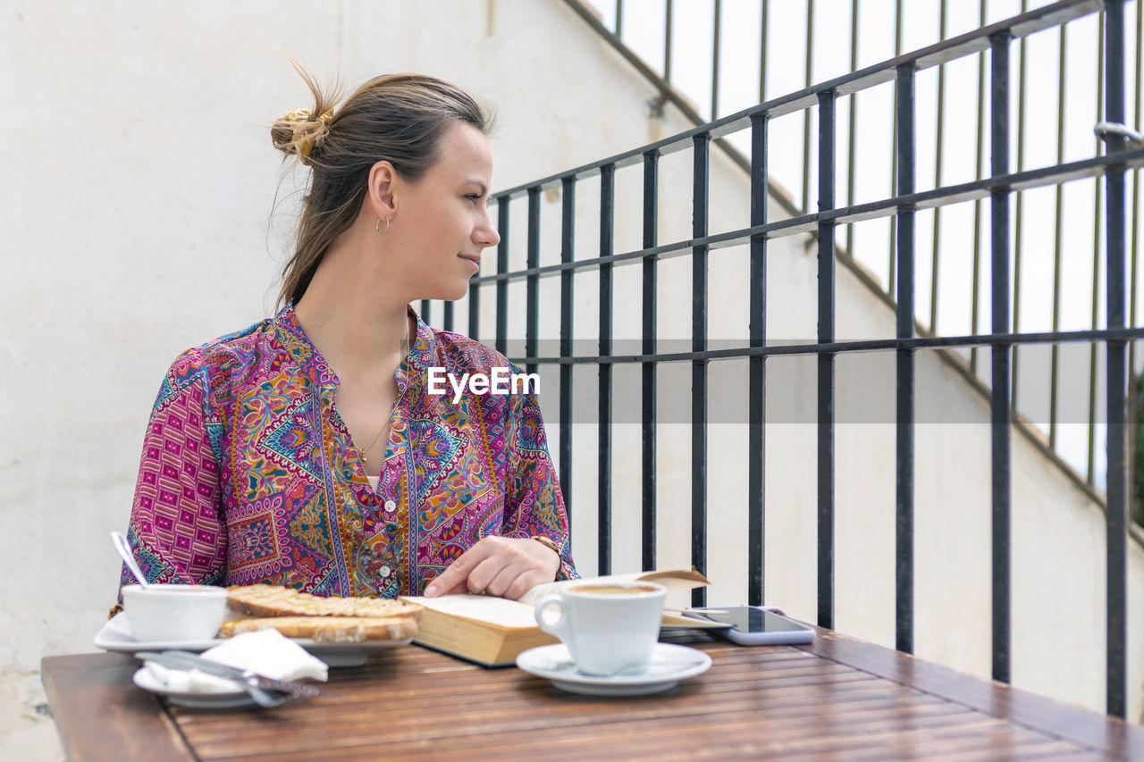 Young woman having toast for breakfast at a bar terrace