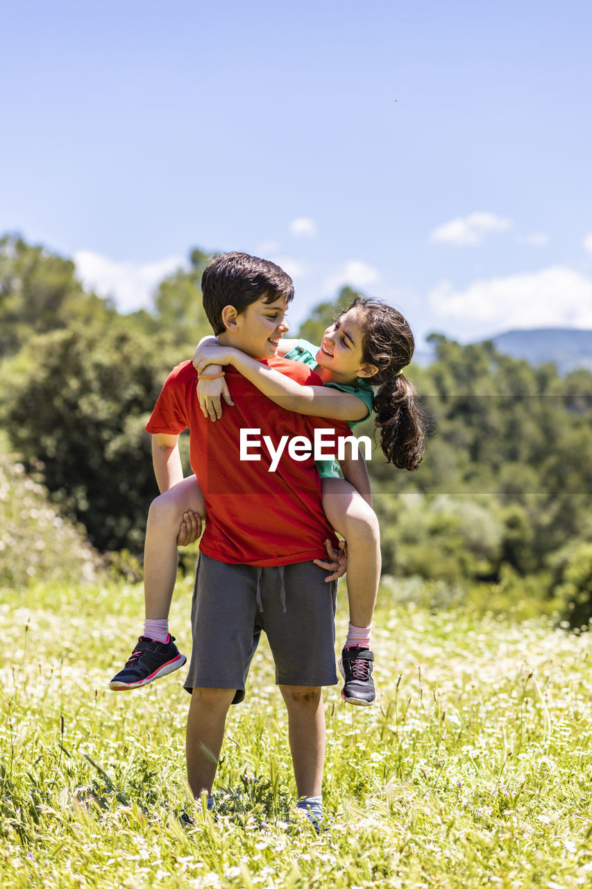 Full length of brother standing with girl on field