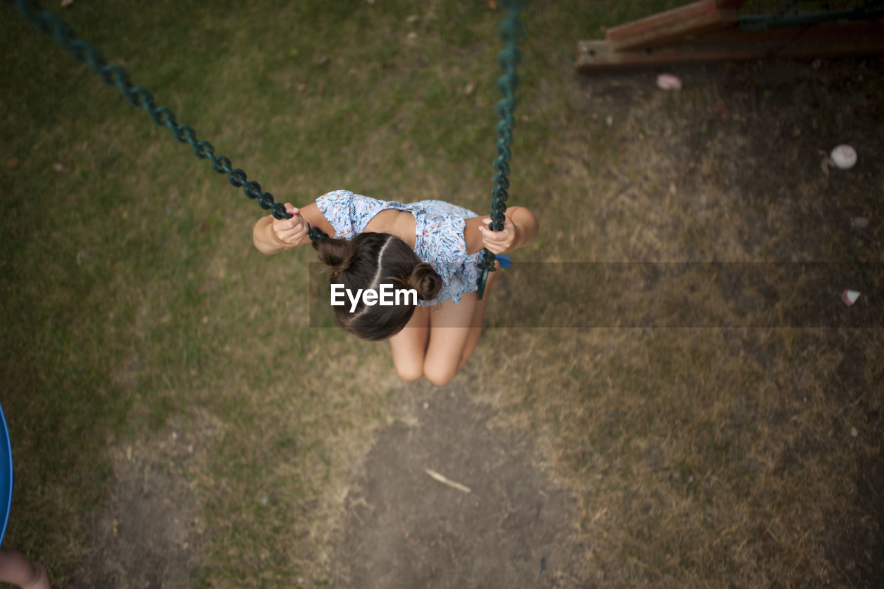 High angle view of girl swinging at playground