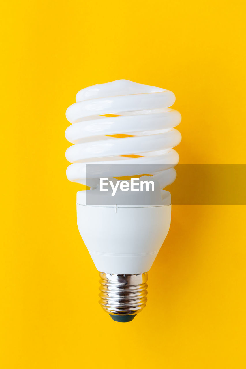 Close-up of light bulb against yellow background