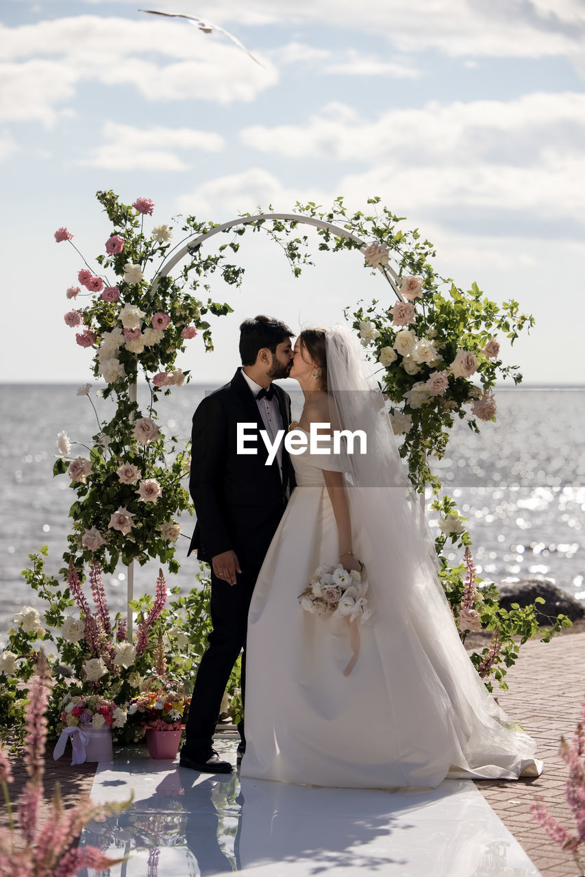 low section of bride and bridegroom holding bouquet