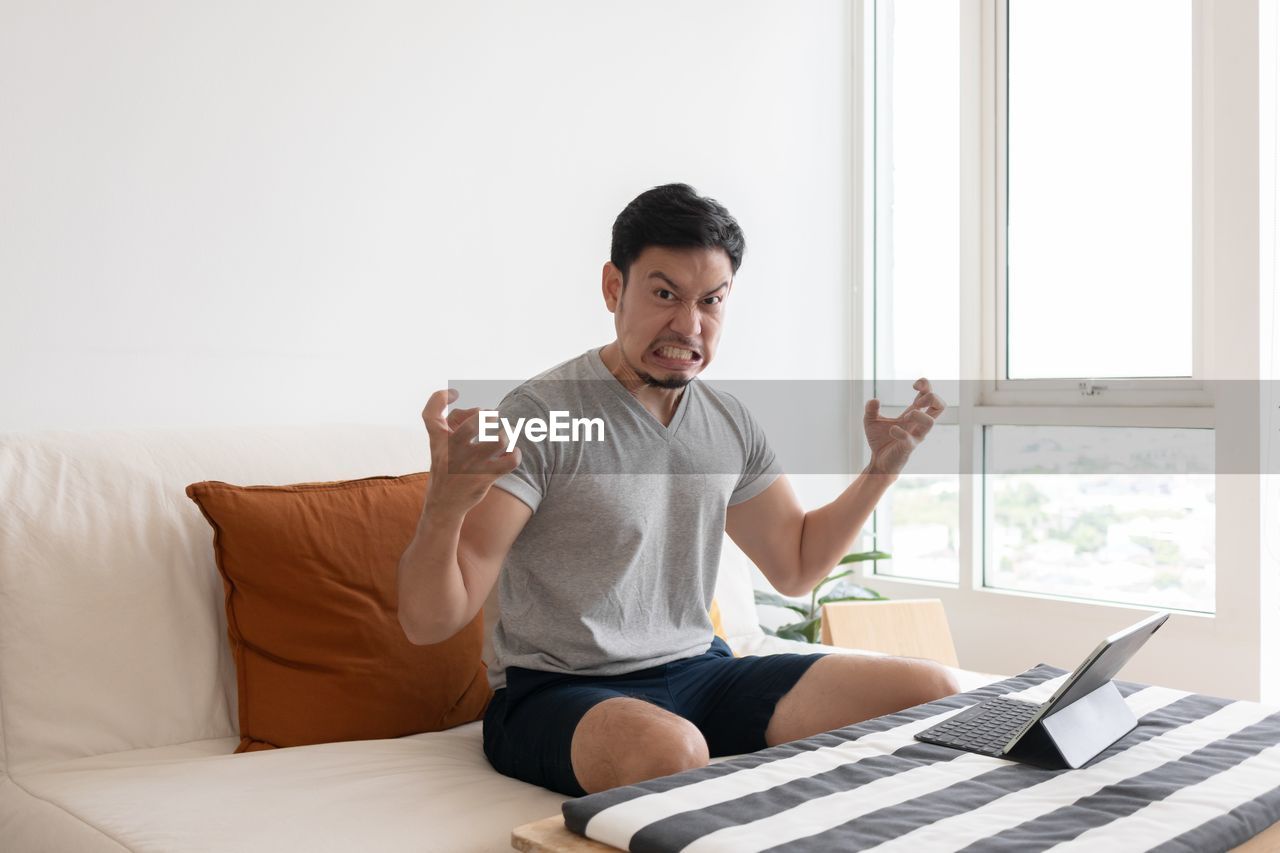 side view of woman using laptop while sitting on sofa at home