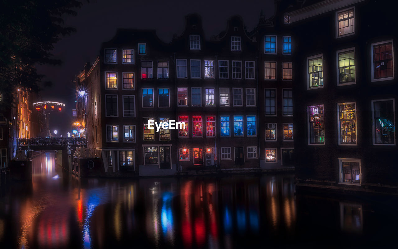 ILLUMINATED BUILDING BY RIVER AT NIGHT