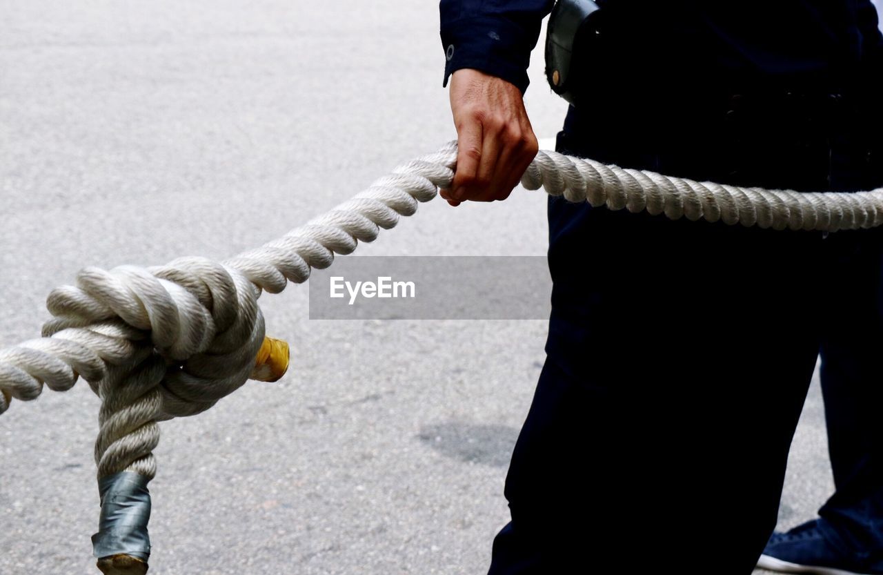 Midsection of person holding rope 