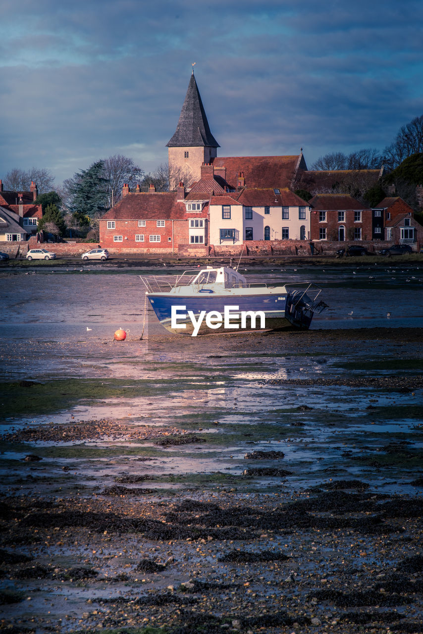 Stranded boat in bosham quay with buildings in the background