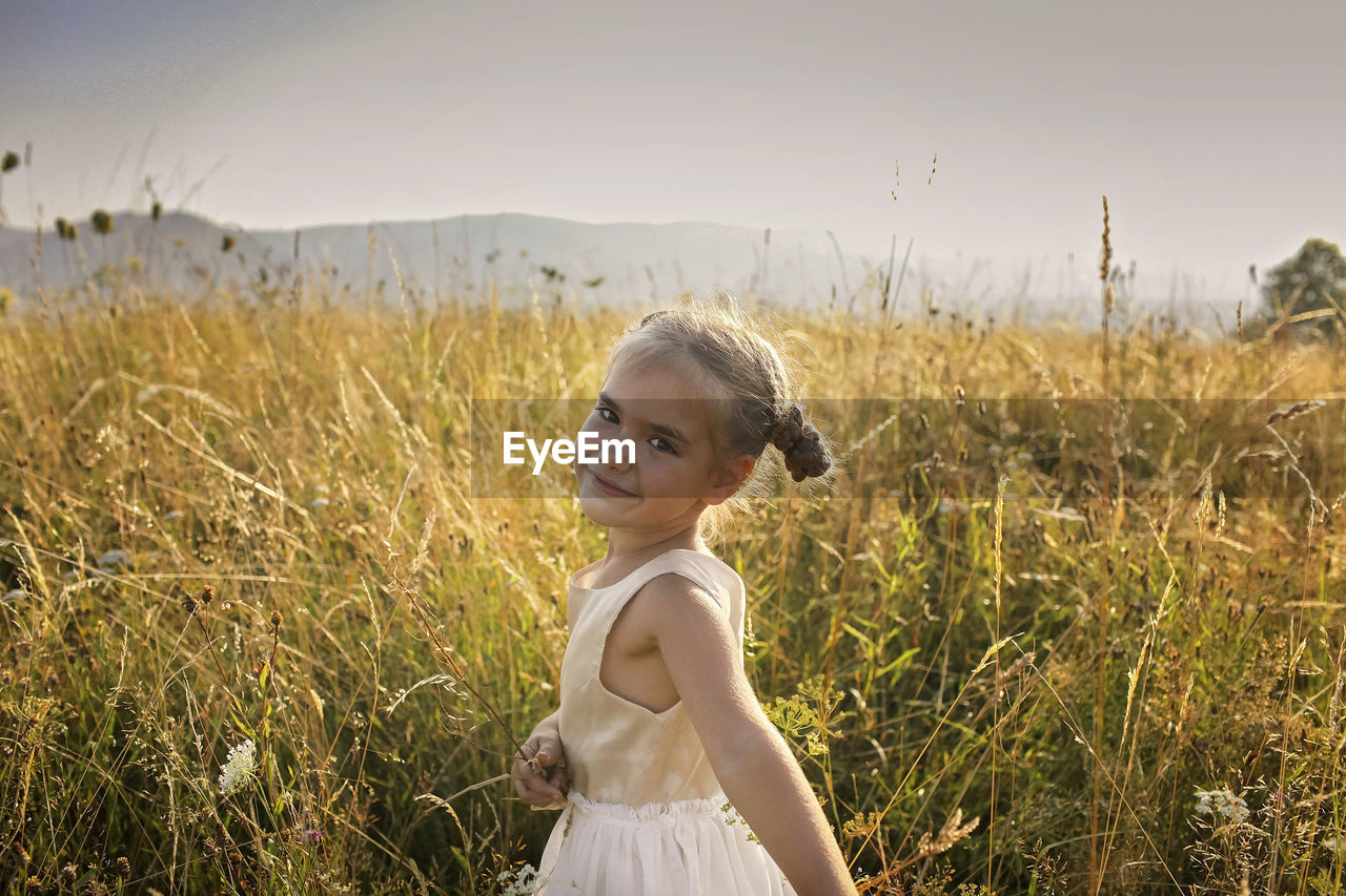 Portrait of woman standing on field against sky