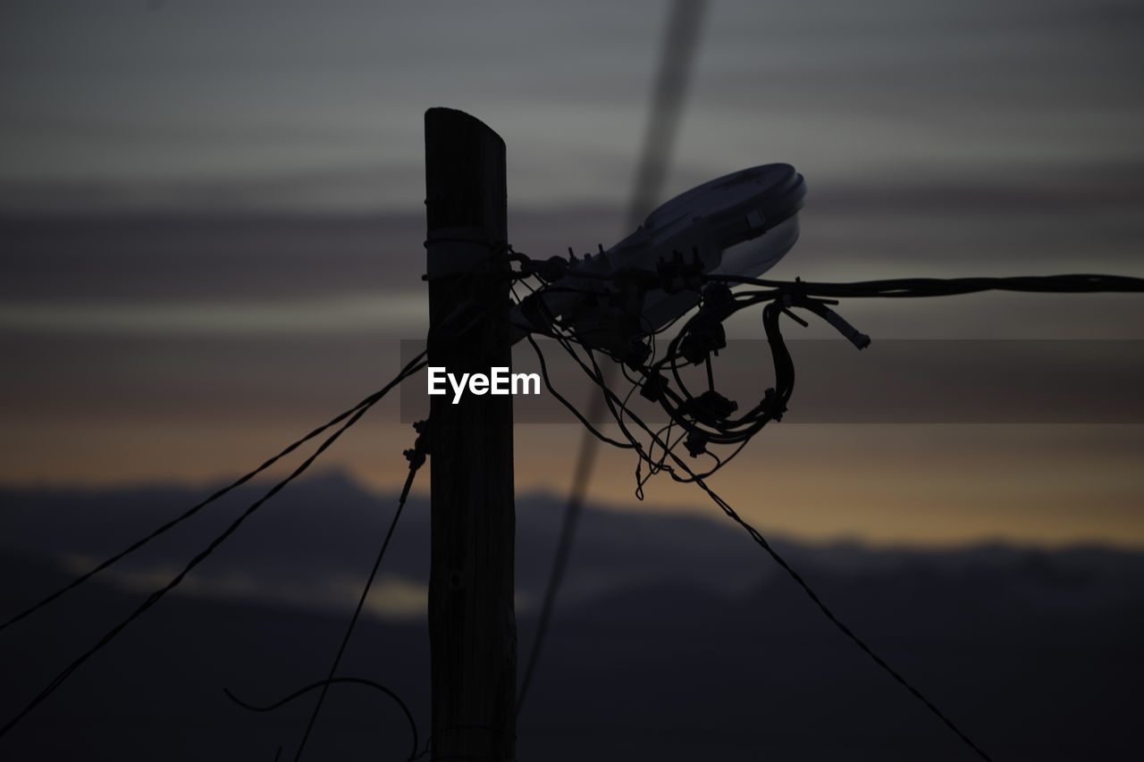 Low angle view of silhouette cables against sky at sunset