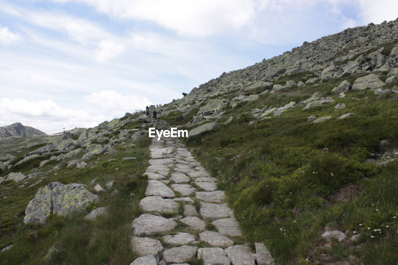 FOOTPATH LEADING TOWARDS MOUNTAINS AGAINST SKY