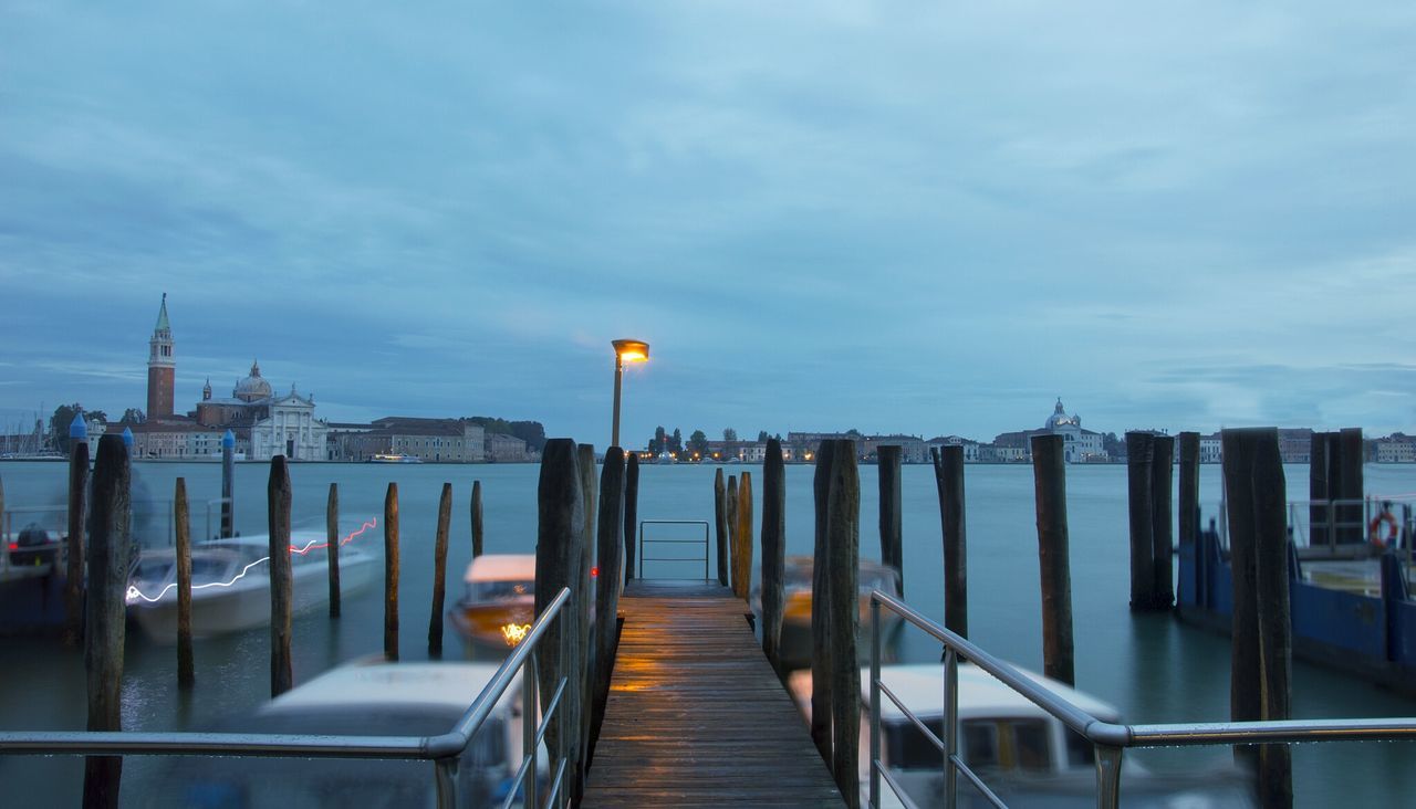 Blurred motion of boats moored in grand canal with church of san giorgio maggiore against cloudy sky