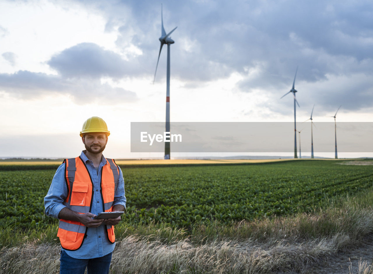 Engineer holding tablet pc standing at wind farm