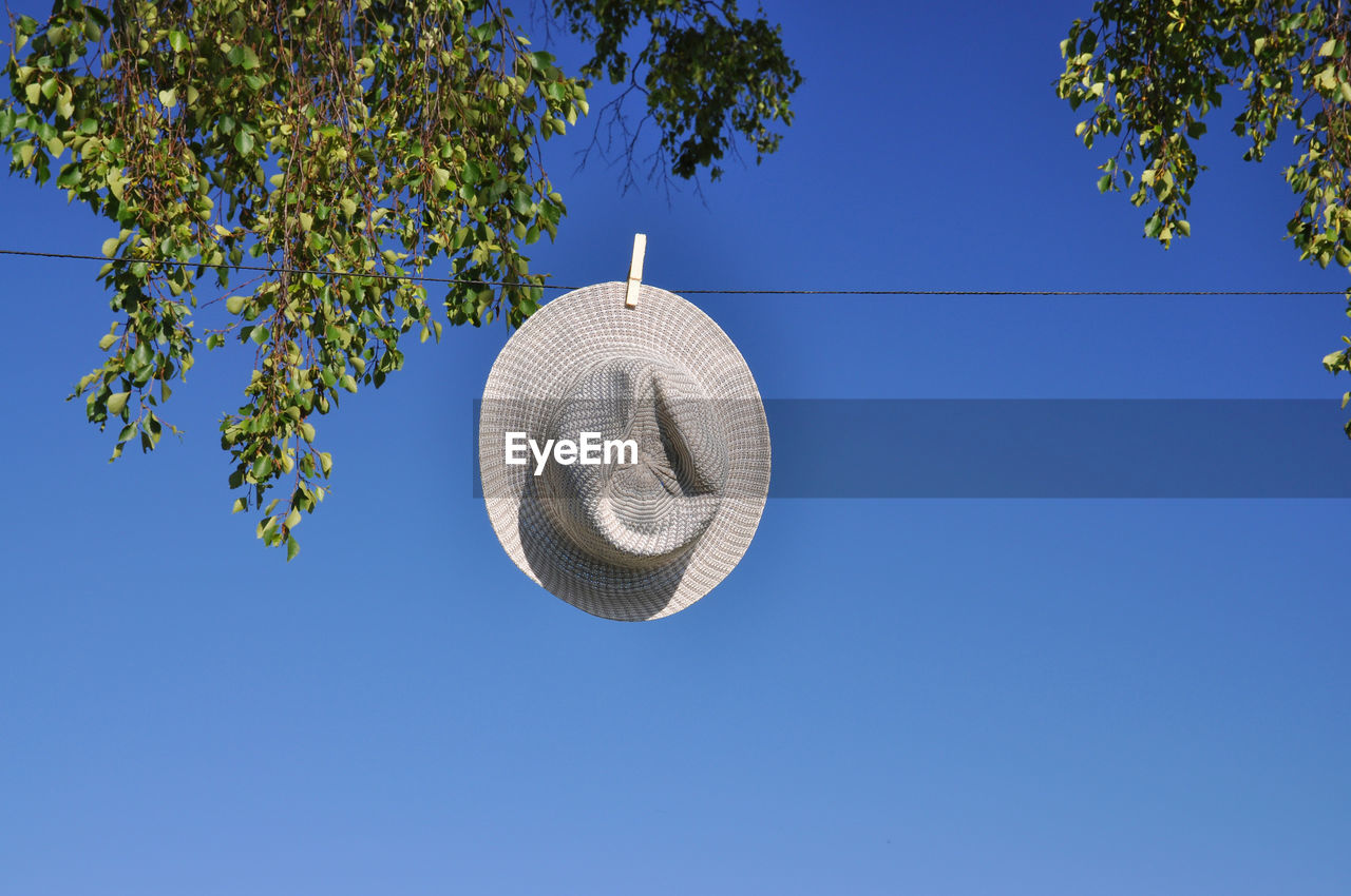Low angle view of sun hat drying on clothesline against clear sky