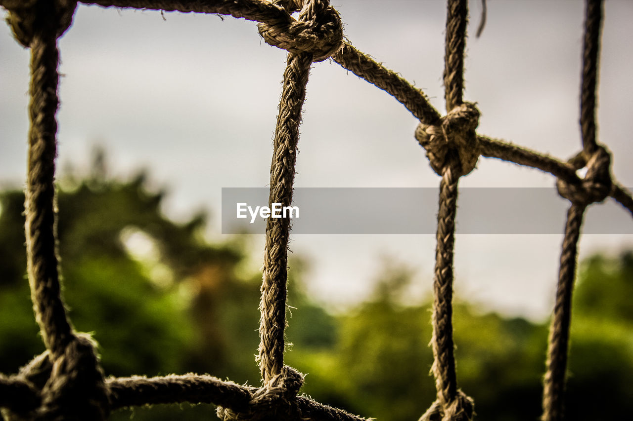 CLOSE-UP OF ROPE TIED ON RUSTY METAL CHAIN