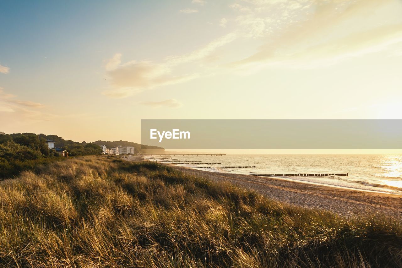 Scenic view of beach against sky at sunset