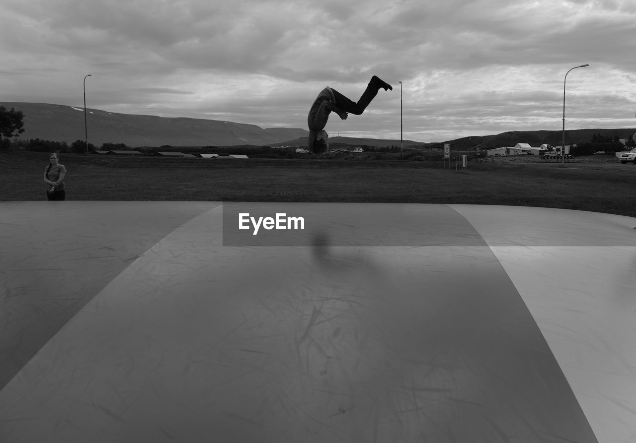 Full length of boy skateboarding against cloudy sky