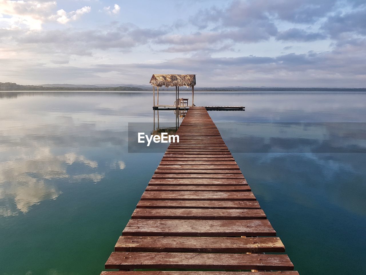 Wooden jetty on pier in lake against sky