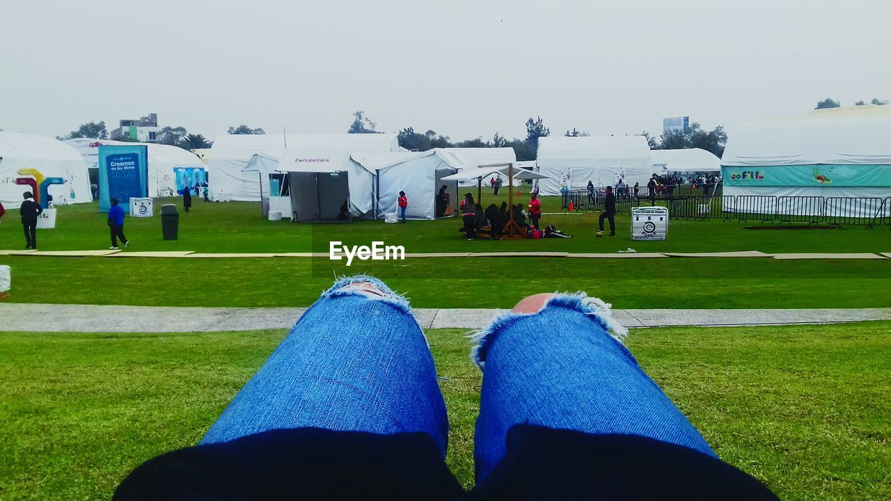 LOW SECTION OF MAN AND WOMAN RELAXING ON GRASSLAND