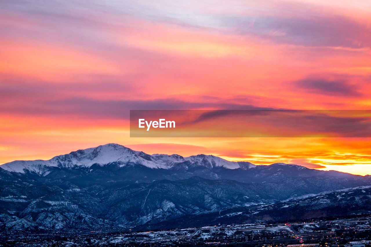 Scenic view of snowcapped mountains against orange sky