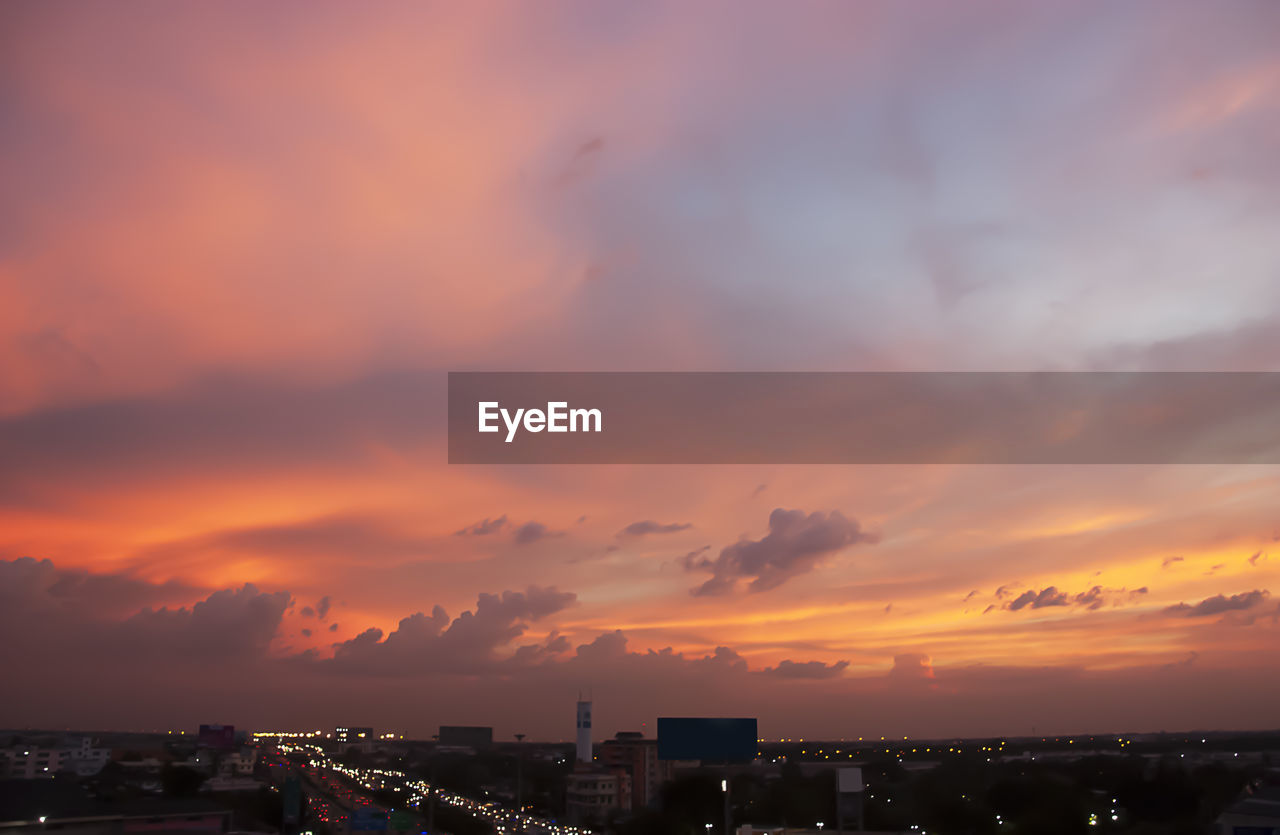 Cityscape against dramatic sky during sunset