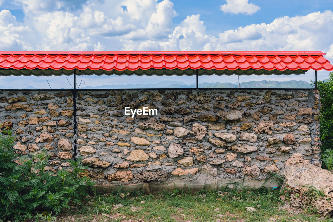 architecture, cloud, sky, nature, built structure, wall, no people, day, plant, wall - building feature, building exterior, outdoors, red, stone wall, grass, land, rural area, landscape, roof, building, fence, protection