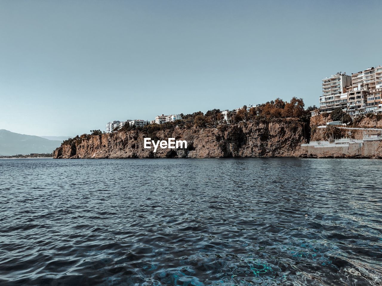 Sea by buildings against clear sky